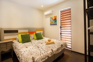 sypialnia z łóżkiem z zielonymi i pomarańczowymi poduszkami w obiekcie Villa Sol Paraiso w mieście Jan Thiel