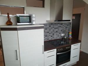 eine Küche mit weißen Schränken und einer Mikrowelle in der Unterkunft Deichgraf in Husum