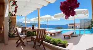 a patio with a table and chairs and umbrellas at Lycia Hotel in Kaş