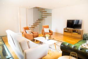 a living room with a couch and chairs and a tv at The Holborn Lights - Modern 3BDR Home with Rooftop Terrace & Garage in London