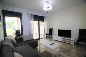 sala de estar con sofá, TV y mesa en Oasis Beach Sonia, en Orihuela Costa