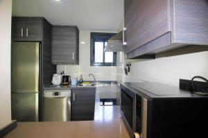 a kitchen with stainless steel appliances and wooden cabinets at Oasis Beach Sonia in Orihuela Costa