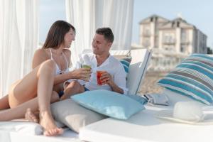 a man and woman sitting on a bed with drinks at Hotel Liberty Beach - Parking & Beach included in Riccione