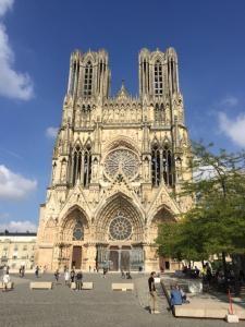 a large cathedral with people sitting in front of it at Hôtel des Arcades in Reims