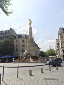 Una statua in mezzo a una strada con edifici di Hôtel des Arcades a Reims