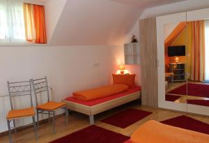 Habitación con cama con almohadas de color naranja en Ferienwohnung am Wörthersee Villa Waldbach, en Krumpendorf am Wörthersee