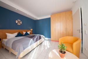 ヴィーク・アウフ・リューゲンにあるInselquartett - Fewo Hiddenseeの青い壁のベッドルーム1室、ベッド1台、椅子1脚が備わります。
