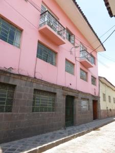 um edifício cor-de-rosa ao lado de uma rua em Tinki Hostel em Cusco