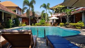 a swimming pool with two chairs and a house at Hotel My Lovina in Lovina