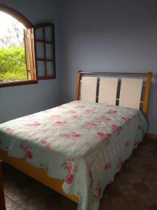 a bedroom with a bed with a flowered blanket on it at Casa de Campo com Piscina in Itupeva