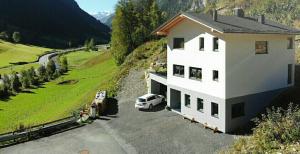 une voiture blanche garée devant une maison dans l'établissement Apartment Eckert, à Feichten Im Kaunertal
