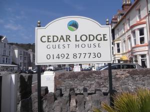 a sign for a guest house on a street at Cedar Lodge in Llandudno