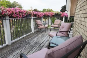 a row of chairs sitting on a deck with pink flowers at Avery House B&B in Stratford