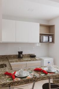 uma cozinha com armários brancos e uma mesa com arcos vermelhos em Star Apart Hotel em Teófilo Otoni