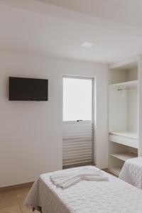 a white bedroom with a bed and a window at Star Apart Hotel in Teófilo Otoni