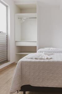a white bedroom with a bed and a window at Star Apart Hotel in Teófilo Otoni