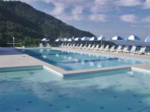 a large swimming pool with chairs and umbrellas at Apartamento Porto Real Suítes in Mangaratiba