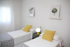 ムルシアにあるApartamento Limon Murciaの白い壁の客室で、ベッド2台、黄色の枕が備わります。