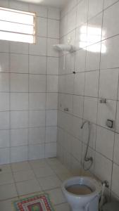 baño blanco con aseo y ventana en Pousada da Sônia, en Uberlândia