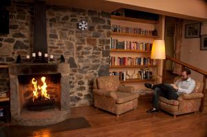 a man sitting in a living room with a fireplace at Hotel Amoretes in La Molina