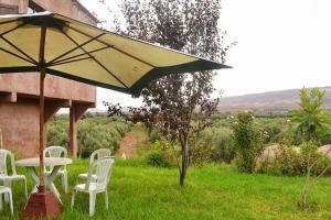 une table, des chaises et un parasol dans l'herbe dans l'établissement Villa Paradise, à Aghmat