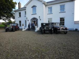 a group of cars parked in front of a white house at The Carriage Houses at Beechpark House in Bunratty