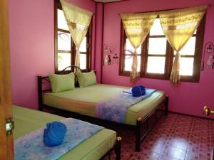 Duas camas num quarto com paredes e janelas cor-de-rosa em Ton Tawan Resort em Ko Kood