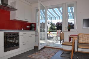 フリードリヒスハーフェンにあるBodenSEE Apartment Friedrichshafen Fischbachのキッチン(白いキャビネット付)、ダイニングルーム(テーブル付)