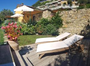 a couple of white lounge chairs on a wooden deck at La Rocca Maison de Charme in Moneglia