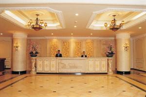 two men standing at the reception desk of a hotel lobby at LK Metropole in Pattaya Central