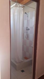 a shower with a white shower curtain in a bathroom at Hostal Open House in San Pedro de Atacama