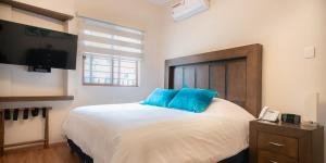 1 dormitorio con 1 cama con almohadas azules y TV en Hotel Posada XR, en Córdoba