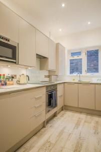 ロンドンにあるBrondesbury Apartmentsの白いキャビネットと電化製品付きの広い白いキッチン