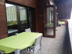 a table and chairs on a porch with a green table at Schwarzwald - Villa Appartments Titisee in Titisee-Neustadt