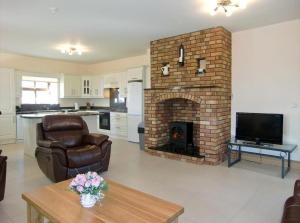 a living room with a brick fireplace with two chairs at Caherush Lodge in Quilty