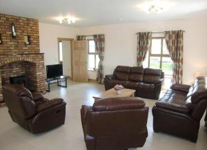 a living room with leather furniture and a fireplace at Caherush Lodge in Quilty