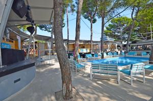 a swimming pool with blue chairs and a tree at Apartment and Room Ivica in Vodice