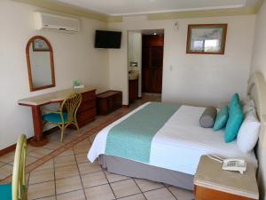 a bedroom with a bed and a desk and a table at Hotel Playa Marina in Mazatlán