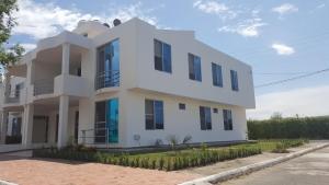 a white house with black windows on a street at Condominio Santa Hagia Sofia - Casa y 2 apartamentos in Flandes