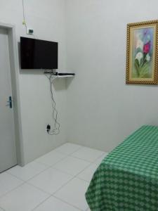 Habitación con cama y TV de pantalla plana en la pared. en Hostel Central, en Maragogi