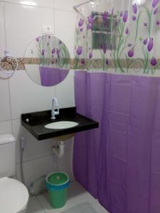 a purple shower curtain in a bathroom with a sink at Hostel Central in Maragogi
