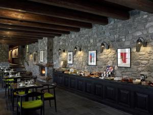Art Mainalon Hotel في فيتينا: مطعم بطاولات وكراسي وجدار حجري