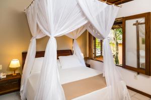 a bedroom with a bed with mosquito nets at Hotel Pousada Coqueiros in Arraial d'Ajuda