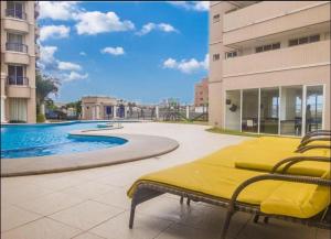 una cama amarilla en un patio junto a una piscina en Apartamento Praia do futuro Bech Village en Fortaleza