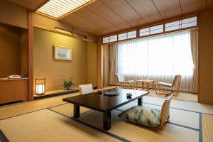 ein Wohnzimmer mit einem Tisch, Stühlen und einem Fenster in der Unterkunft Hotel Apple Land in Hirakawa