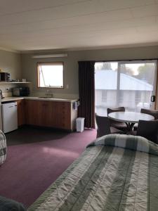 a room with a bed and a table and a kitchen at Lilybrook Motel in Rangiora