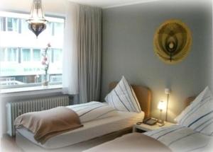 a white bedroom with two beds and a window at CityMinis in Düsseldorf