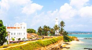 a white building next to the ocean with a lighthouse at Dream Villa Galle Fort in Galle