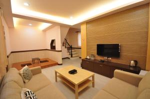 a living room with a couch and a flat screen tv at Seasons Homestay in Xiaoliuqiu