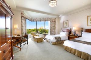 a hotel room with two beds and a desk and a window at Hotel Chinzanso Tokyo in Tokyo